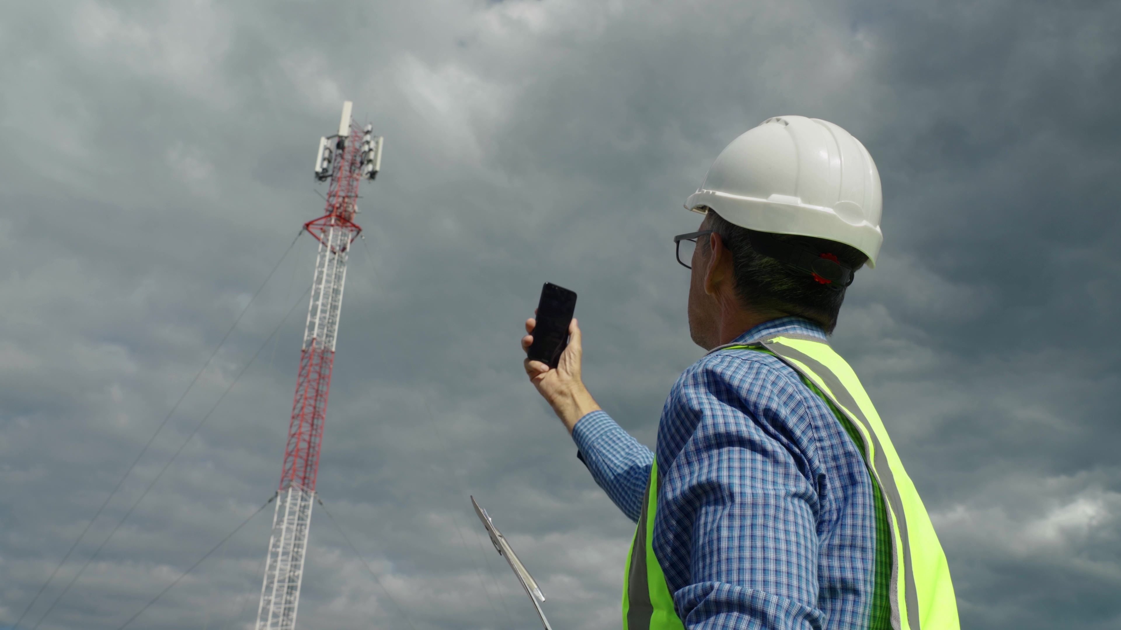 man holding up phone to cell tower performing 5G log analysis