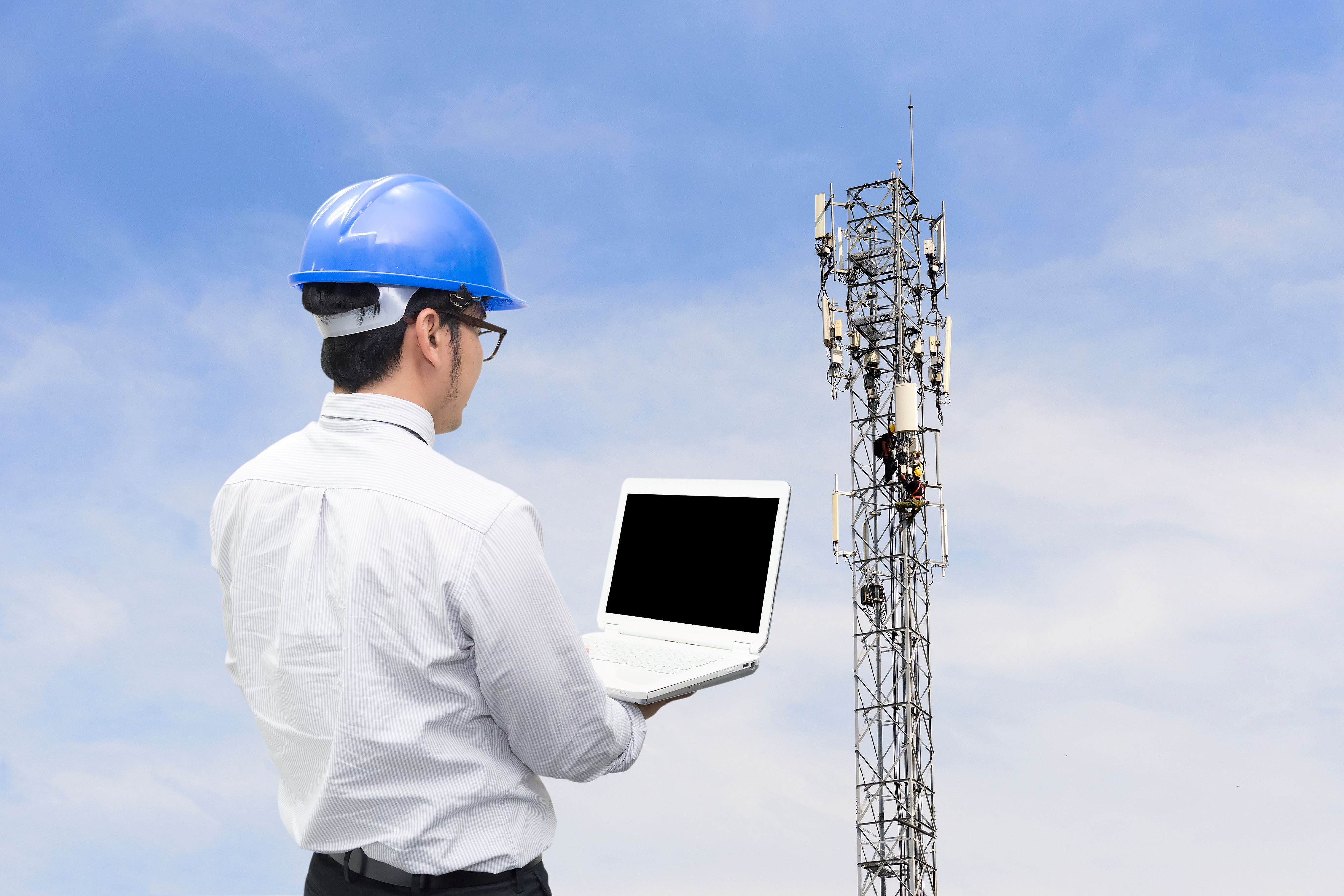 man testing 5G next to cell tower
